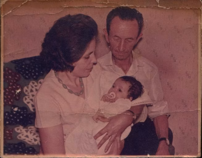 1965 family group photograph faded to a pink cast, with a torn right-hand edge